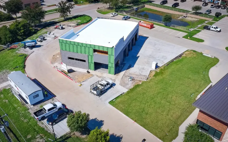 Aerial view of the new Integrity 1st Car Pros building in Anna, Texas, in October 2026: roof complete and service bays open.