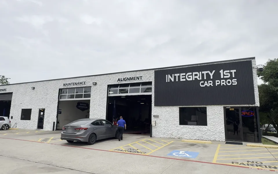 The Integrity 1st Car Pros shop in Grapevine, Texas: a white block building with Maintenance and Alignment bays under the Car Pros sign.