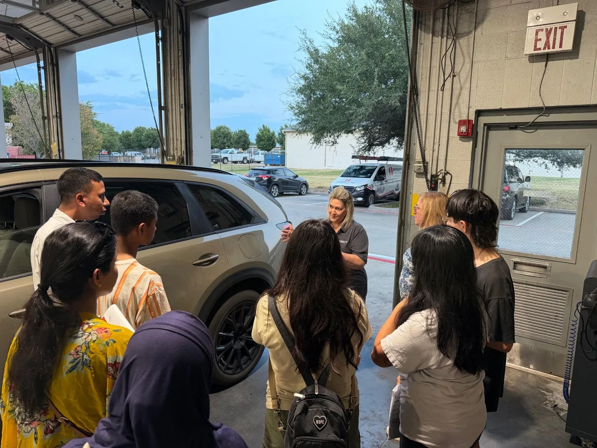 A group gathered around a vehicle during an Auto Care 101 class at the Murphy location