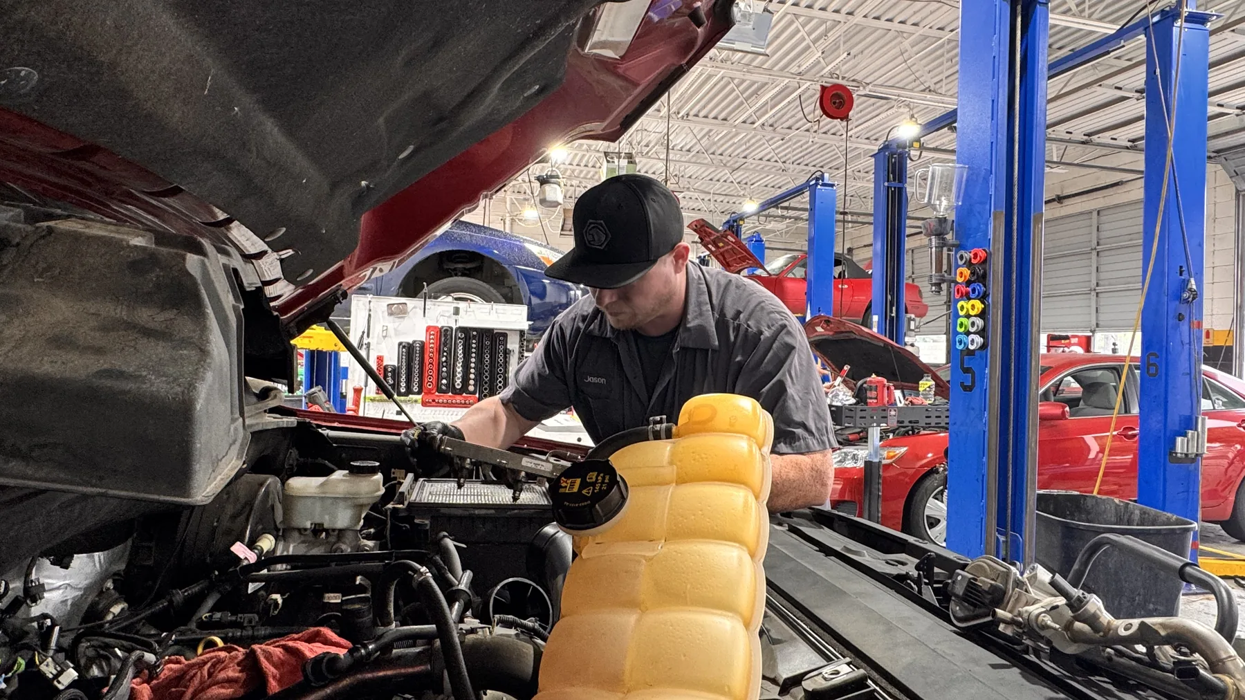 An Integrity 1st Car Pros technician at work under the hood, with the service bay behind