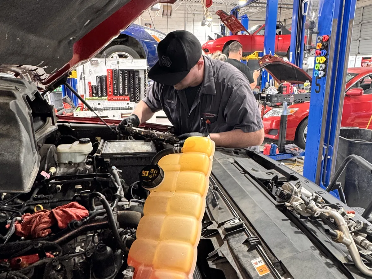 An Integrity 1st technician working under the hood of a vehicle
