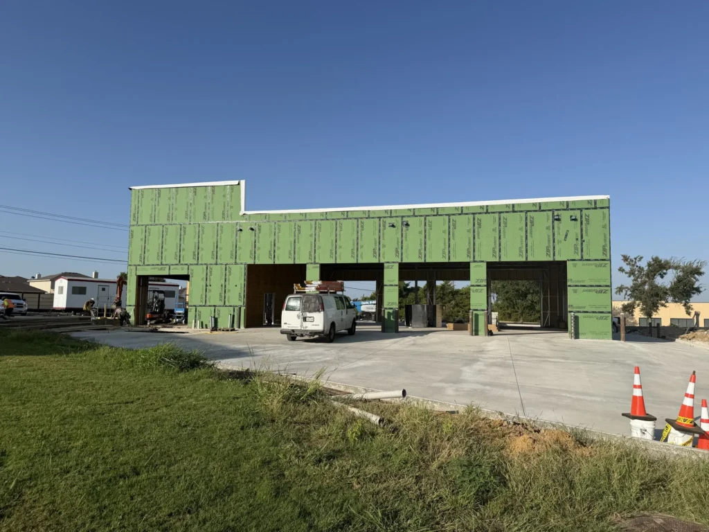 The enclosed shell of the Integrity 1st Car Pros building in Anna, Texas, seen across the finished concrete apron