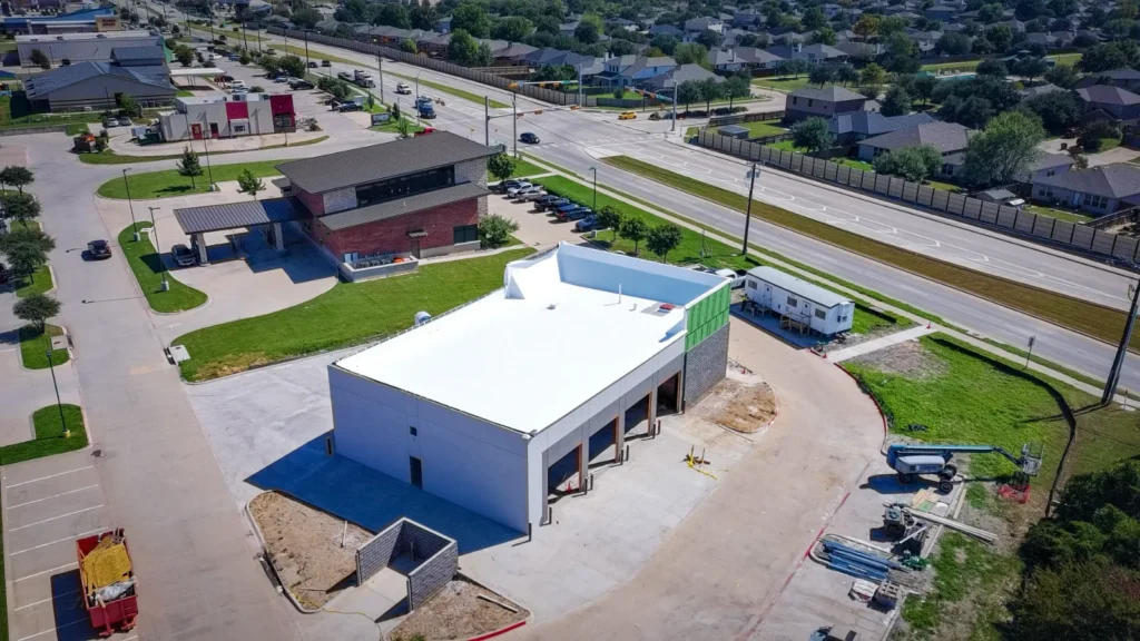 The finished white roof deck of the Anna shop seen from above, with the block trash enclosure being built alongside