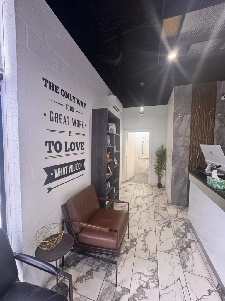 The customer lounge at the Integrity 1st Car Pros shop on Belmont Ave in Dallas, with seating and a marble feature wall