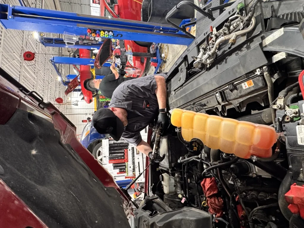 A technician working under the hood of a vehicle in the service bays at the W 15th Street shop